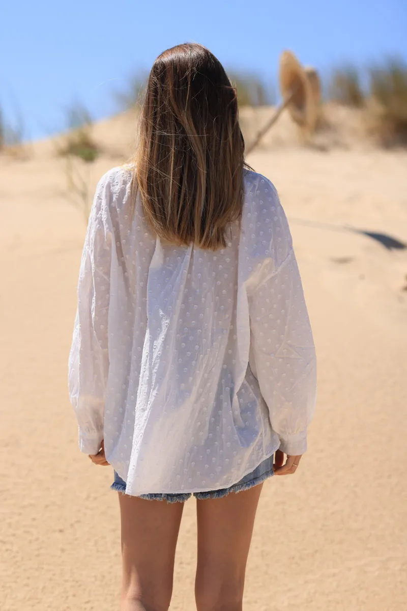 White tunic with raised polka dot pattern and corded collar.