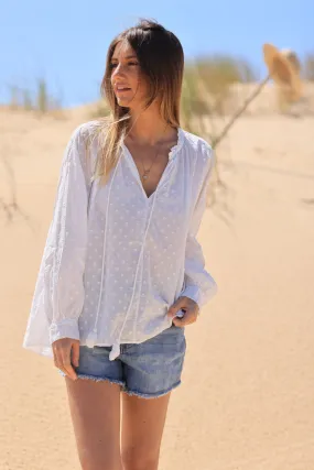 White tunic with raised polka dot pattern and corded collar.