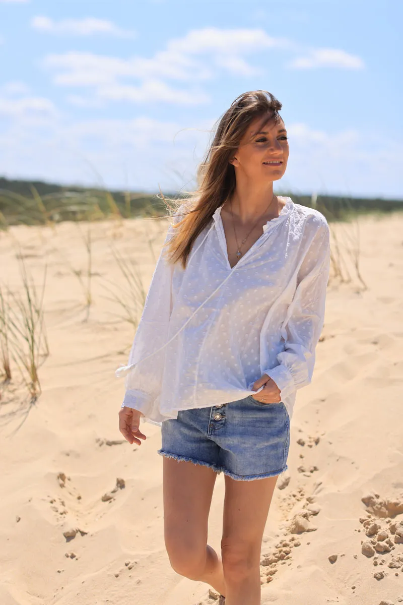 White tunic with raised polka dot pattern and corded collar.